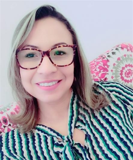 Psicóloga Karla Andrade sorrindo, de óculos